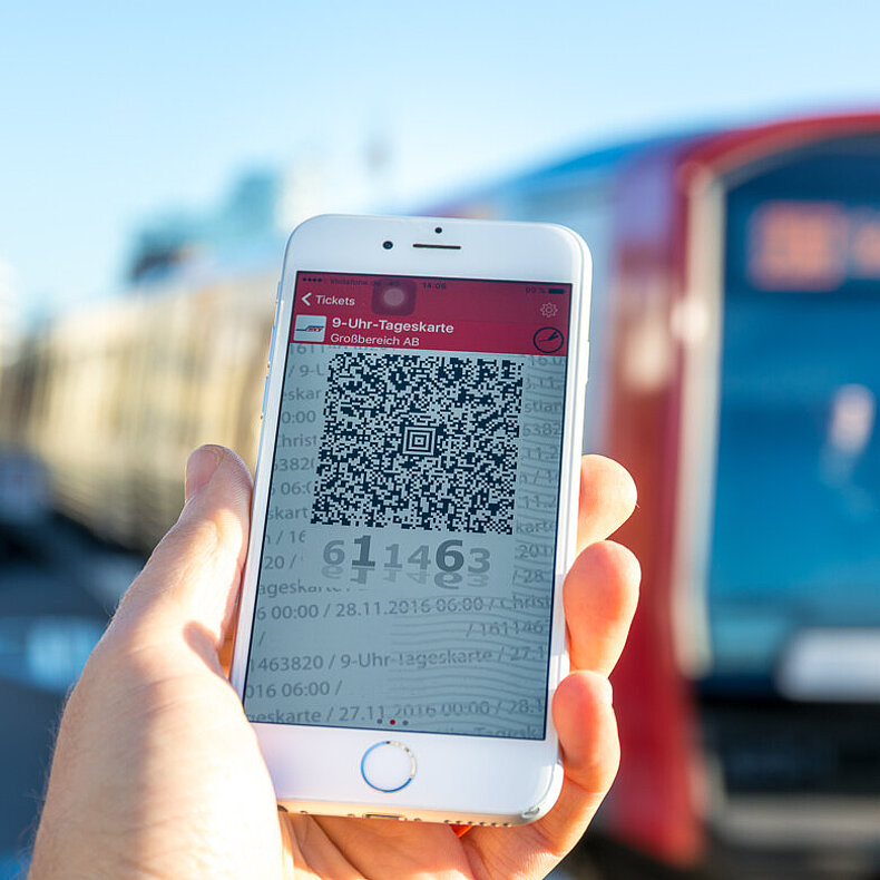 HVV Apps QR-Code auf einem Smartphone Display im Hintergrund verschwommen eine Hamburg U-Bahn